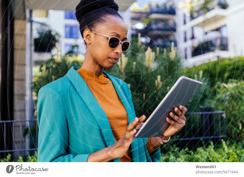Porträt einer jungen Geschäftsfrau mit Sonnenbrille, die ein digitales Tablet im Freien benutzt geschäftlich Geschäftsleben Geschäftswelt Geschäftsperson