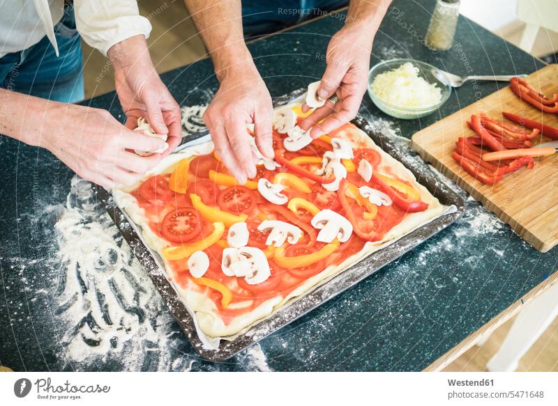 Nahaufnahme eines Paares, das zu Hause in der Küche eine Pizza zubereitet Pärchen Partnerschaft Zuhause daheim zubereiten kochen Essen zubereiten Pizzen Mensch