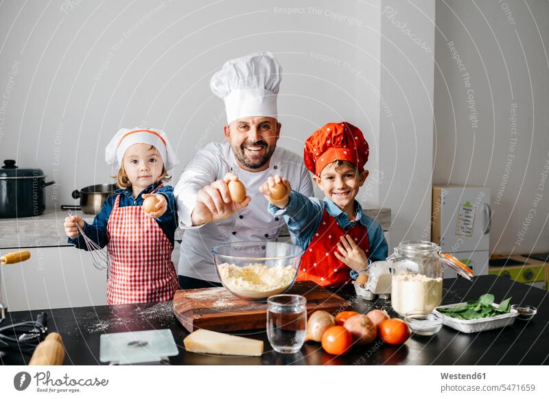 Porträt eines Vaters mit zwei Kindern, die zu Hause in der Küche Teig zubereiten Gastronomie Koeche Kuechenchef Kuechenchefs Köche Küchenchef Küchenchefs Schale