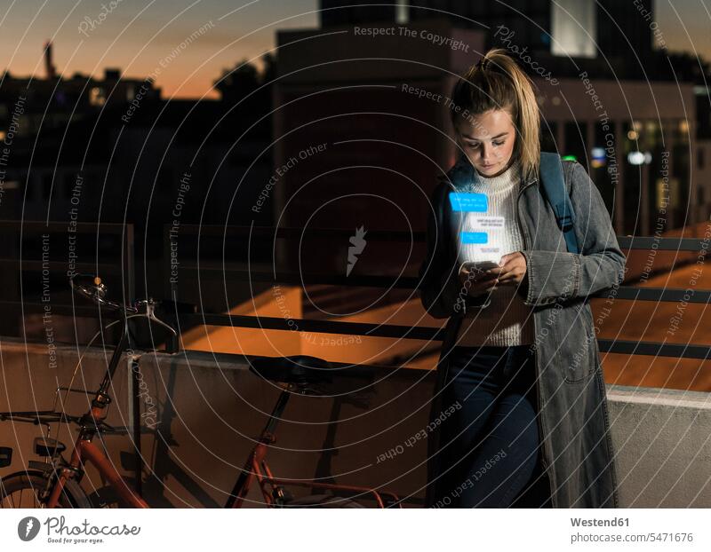 Junge Frau nachts im Freien mit Text aus Smartphone Nacht iPhone Smartphones hervorkommen herauskommen emporsteigen herausragen weiblich Frauen Handy