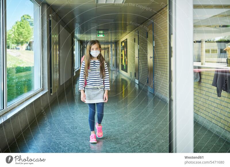 Mädchen mit Maske geht auf dem Schulkorridor Schüler gehen Gesundheit Schutz Sicherheit Schule Flur Vorderansicht Innenaufnahme Portrait Tag Schülerin