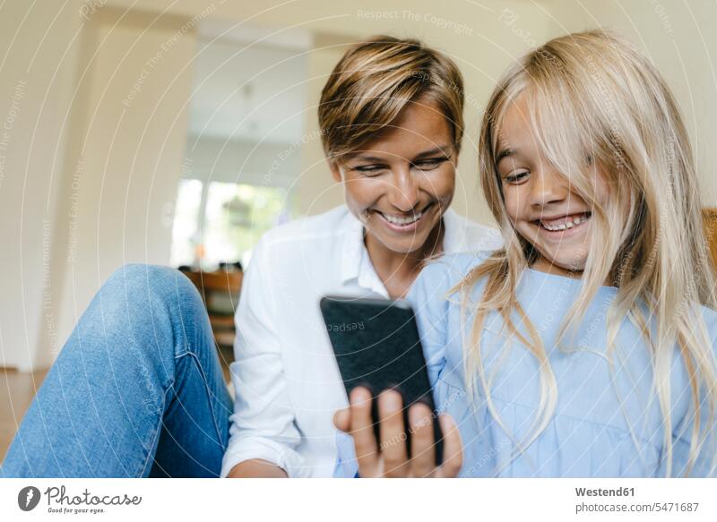 Glückliche Mutter und Tochter Blick auf Smartphone zusammen glücklich glücklich sein glücklichsein Töchter ansehen iPhone Smartphones Gemeinsam Zusammen