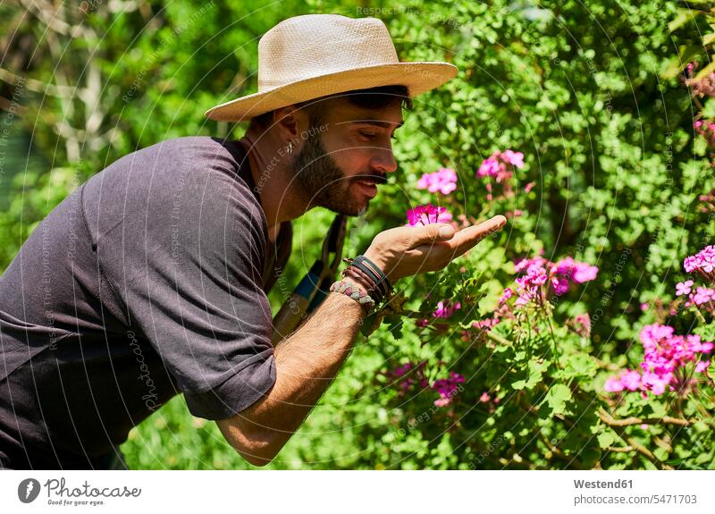 Mann riecht Blumen im Garten Arbeit Jahreszeiten sommerlich Sommerzeit entspannen relaxen entspanntheit relaxt freuen geniessen Genuss Glück glücklich sein