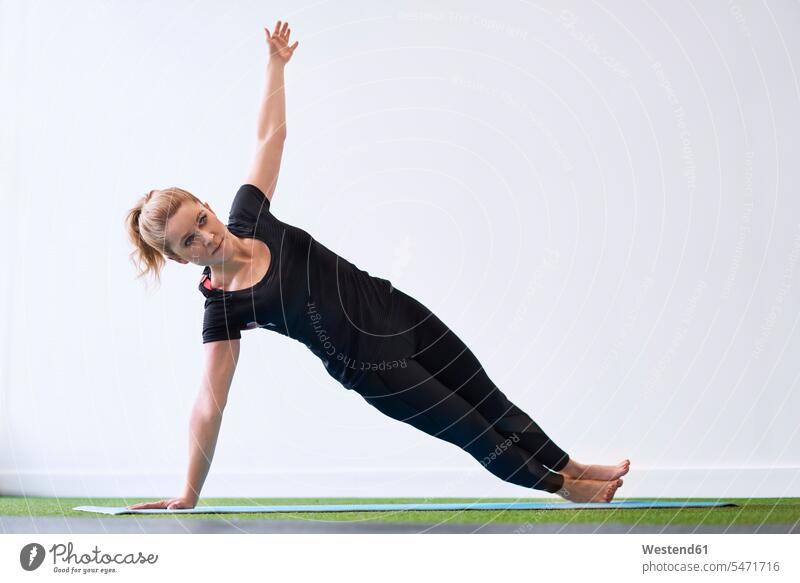 Frau macht Yoga-Übung an den Seitenplanken im Studio trainieren Yoga-Übungen Yogauebungen Yogaübungen Jogauebung Jogauebungen Uebung Uebungen Atelier Studios