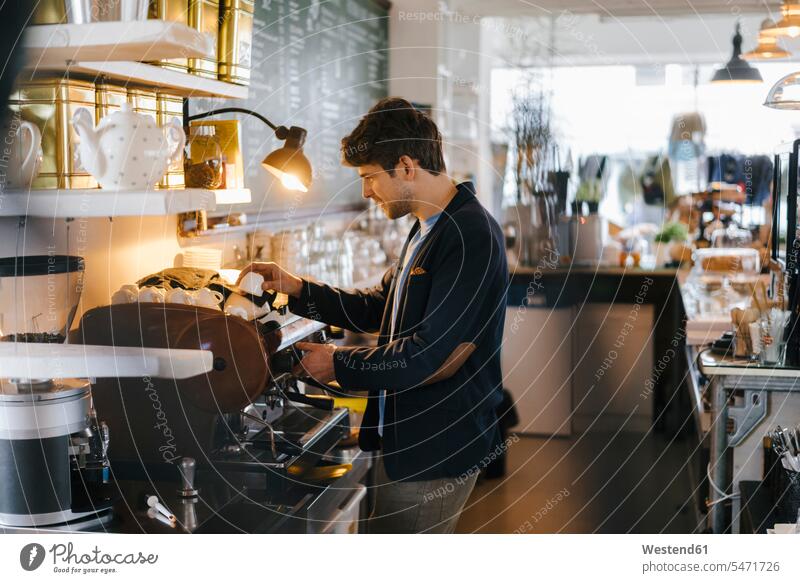 Mann in einem Café, der Tassen sortiert sortieren Sortierung einsortieren Männer männlich Kaffeetasse Kaffeetassen Cafe Kaffeehaus Bistro Cafes Cafés