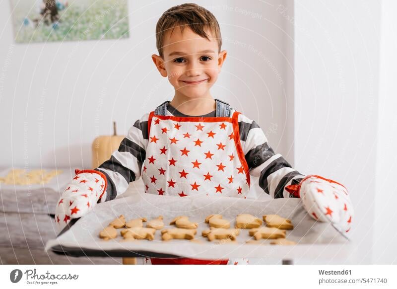 Porträt eines lächelnden kleinen Jungen, der ein Backblech mit selbstgebackenen Keksen hält Portrait Porträts Portraits Plaetzchen Plätzchen Blech Bleche