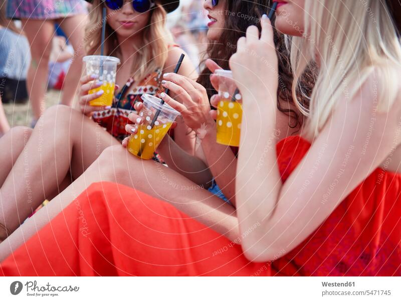 Freunde trinken Saft und sitzen während des Musikfestivals auf der Wiese Musiktage Musikfestspiele Freundinnen Frau weiblich Frauen Spaß Spass Späße spassig