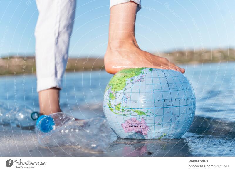 Der Fuß des Menschen auf dem Strandball der Erde, Nahaufnahme Rohstoffe Erdkugel Globen Weltkugel Plastik entspannen relaxen Jahreszeiten sommerlich Sommerzeit