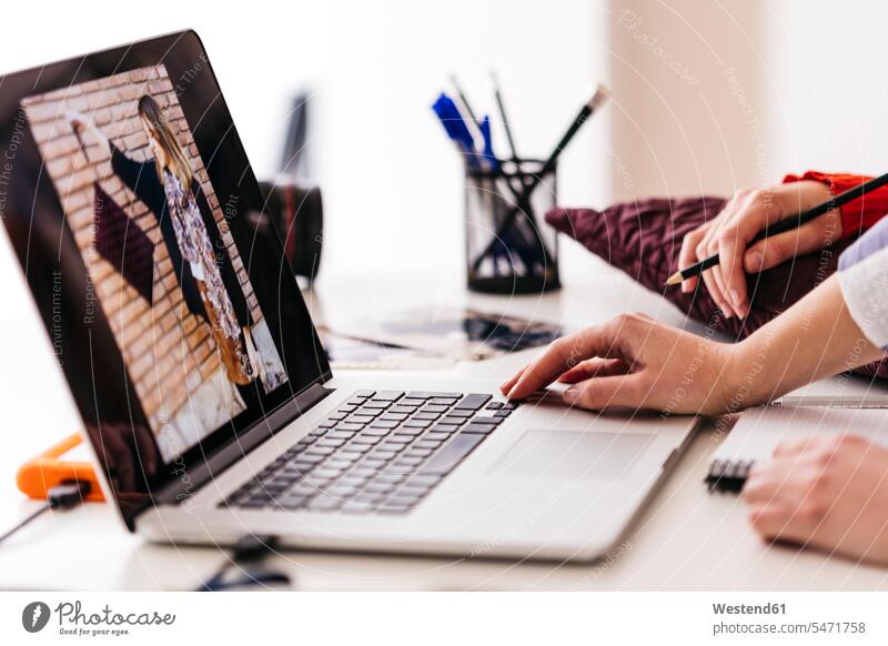 Nahaufnahme von zwei Modedesignern, die an einem Foto auf einem Laptop arbeiten Fotos Frau weiblich Frauen modisch Fashion Designerin Designerinnen Notebook