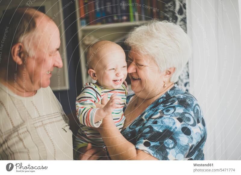 Glückliche Großeltern halten ihren kleinen Enkel Leute Menschen People Person Personen Europäisch Kaukasier kaukasisch Gruppe von Menschen Menschengruppe