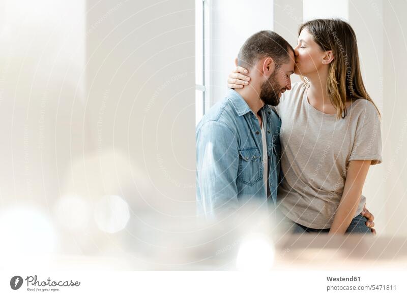 Verliebtes Paar am Fenster ihres Hauses Kuss Küsse sitzend sitzt Arm umlegen Umarmung Umarmungen entspannen relaxen entspanntheit relaxt freuen geniessen Genuss