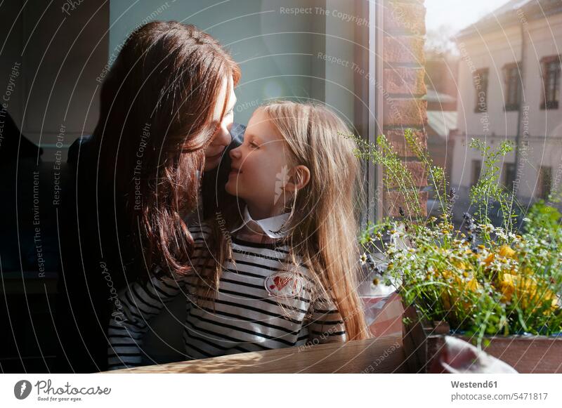 Lächelndes Mädchen mit ihrer Mutter in einem Cafe Fensterscheiben sitzend sitzt behüten behütet geborgen Sicherheit Glück glücklich sein glücklichsein innig nah