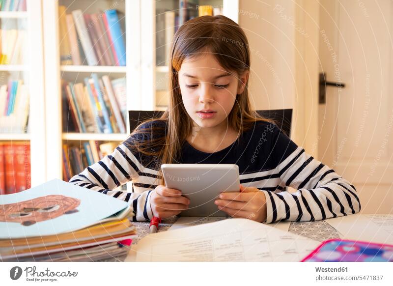 Mädchen macht Hausaufgaben mit digitalem Tablett Ablage Regale Bücherregale Tische Stifte Füllfederhalter Lektüre sitzend sitzt daheim zu Hause Technik