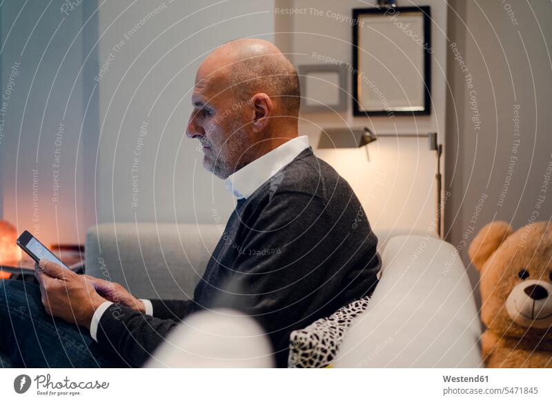 Älterer Mann sitzt auf Couch, liest Buch Tablet Tablet Computer Tablet-PC Tablet PC iPad Tablet-Computer lesen Lektüre Komfortabel Gemütlich Bequem bequem