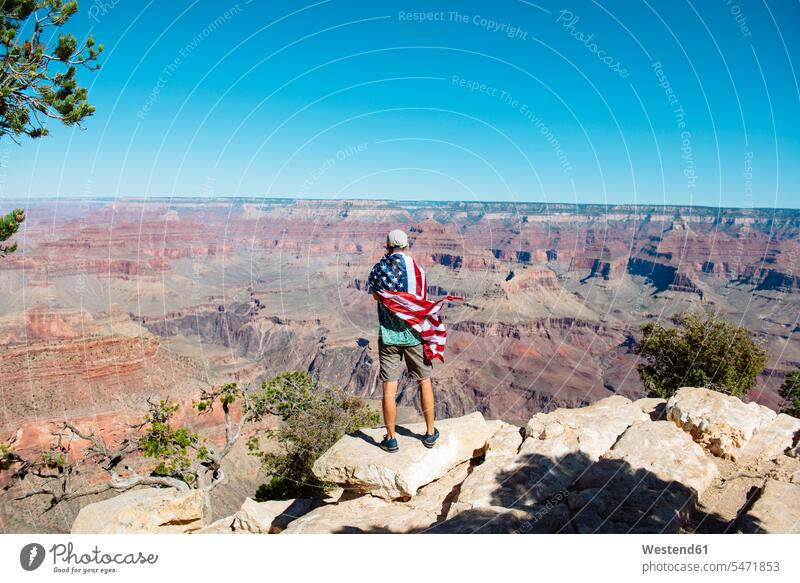 USA, Arizona, Rückenansicht eines in eine amerikanische Flagge gehüllten Mannes mit Blick auf den Grand Canyon National Park genießen geniessen Genuss Aussicht