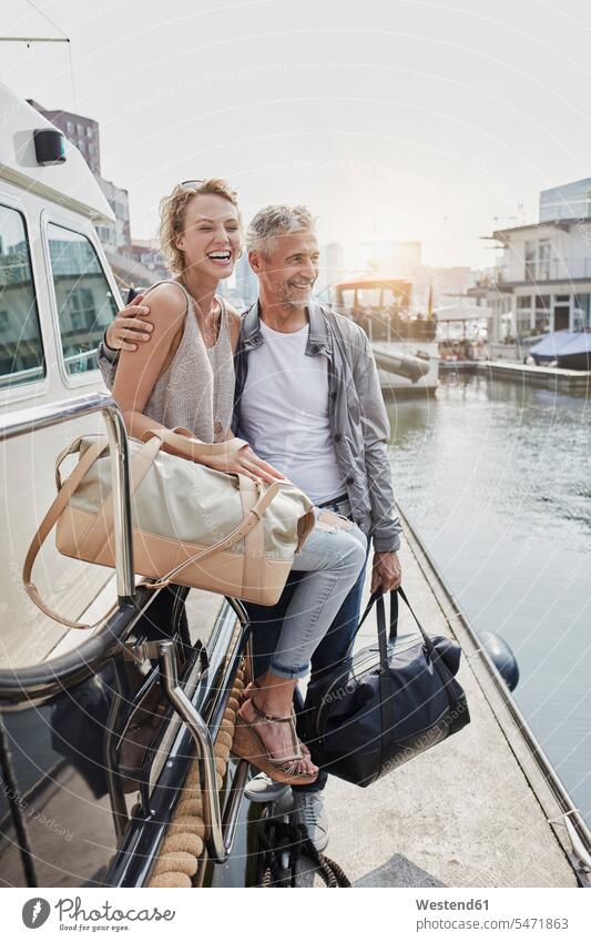 Älterer Mann und junge Frau stehen mit Reisetaschen auf dem Steg neben der Jacht stehend steht Yacht Yachten Jachten Stege Anlegestelle Paar Pärchen Paare