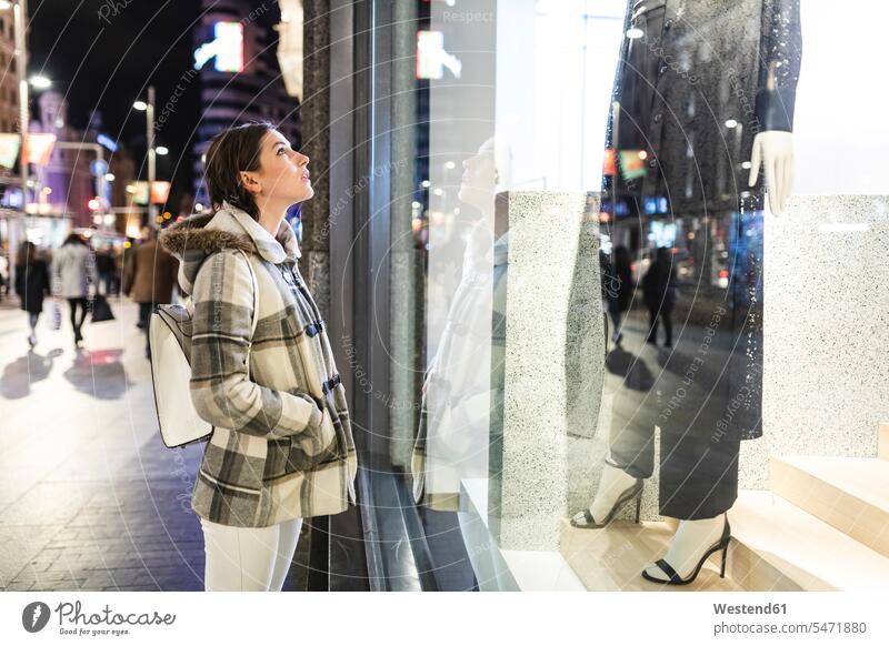 Spanien, Madrid, junge Frau in der Stadt in der Nacht neben Gran Via Blick auf ein Schaufenster weiblich Frauen staedtisch städtisch nachts Erwachsener