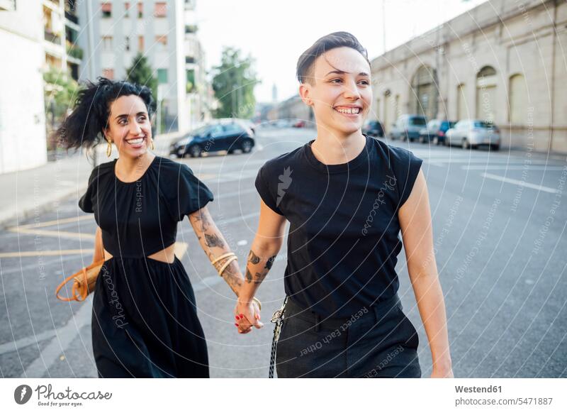 Lächelndes lesbisches Paar geht in der Stadt spazieren Farbaufnahme Farbe Farbfoto Farbphoto Außenaufnahme außen draußen im Freien Tag Tageslichtaufnahme