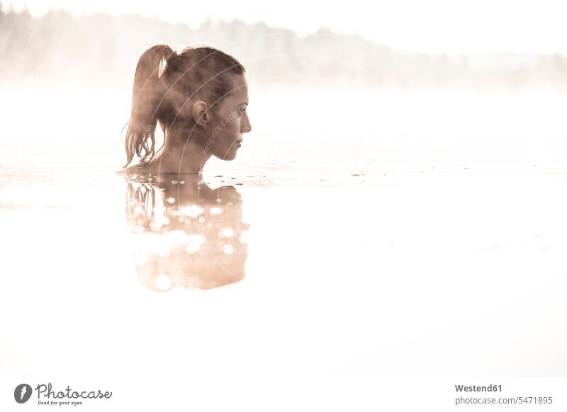 Frau badet im Morgennebel in einem See früh Frühe entspannen relaxen entspanntheit relaxt geniessen Genuss Naesse Nässe stimmungsvoll erfrischen erfrischend