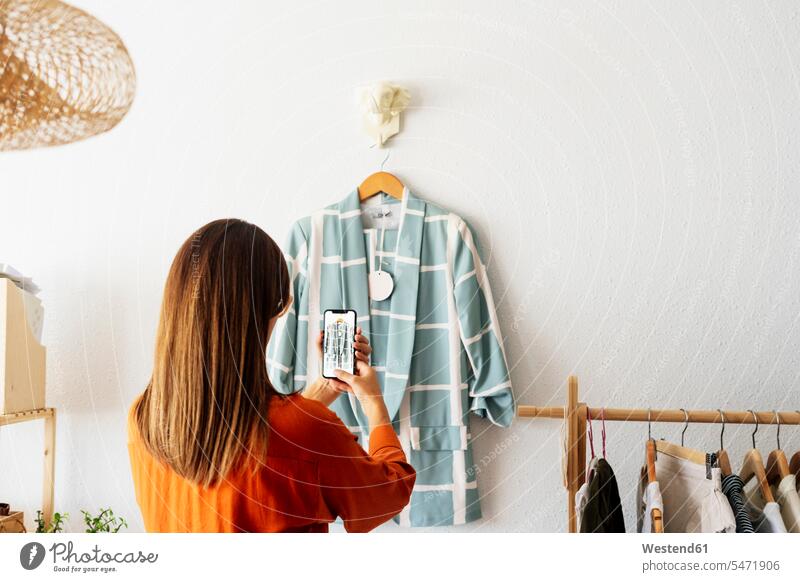 Zu Hause arbeitende Modedesignerin fotografiert Kleidungsstück mit dem Smartphone Job Berufe Berufstätigkeit Beschäftigung Jobs geschäftlich Geschäftsleben