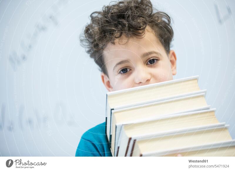 Porträt eines Schuljungen, der im Unterricht Bücher trägt Buch Portrait tragen Schüler Schule Schulklasse Weißwandtafel Tafel Stapel Ehrgeiz positiv Wissen