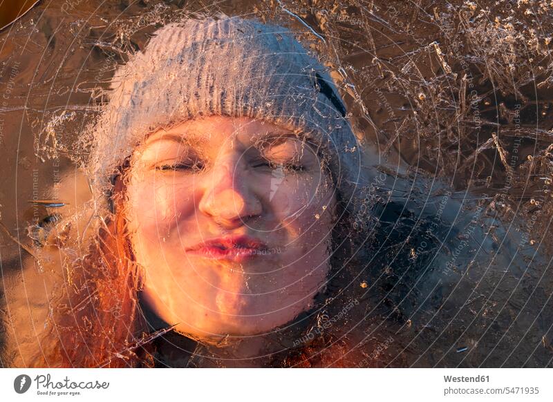 Porträt einer Teenagerin mit lustigem Gesicht hinter eisbedeckter Oberfläche Jahreszeiten winterlich Winterzeit Kälte witzig humorvoll spaßig Oberflaeche Spass