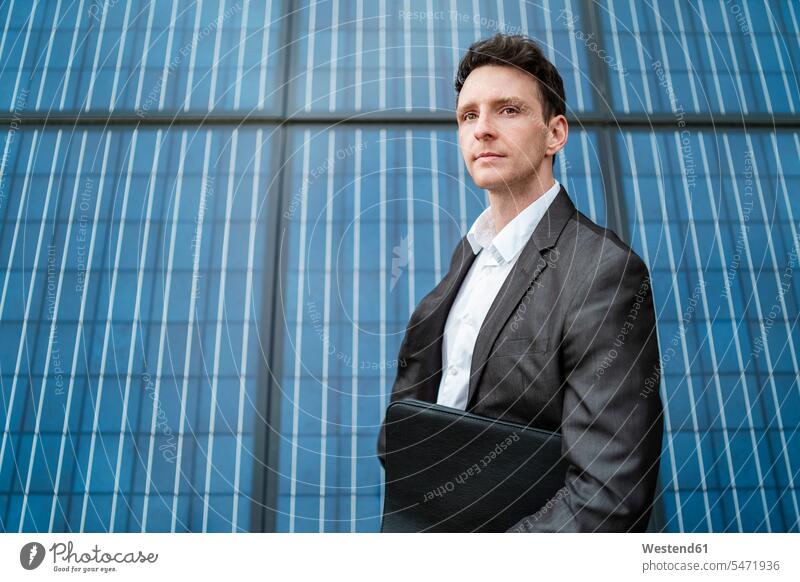 Geschäftsmann hält Ordner vor Sonnenkollektoren stehend Photozellen Solarzellen Sonnenzellen lichtelektrische Zellen steht halten Mappe Mappen Solarpanel