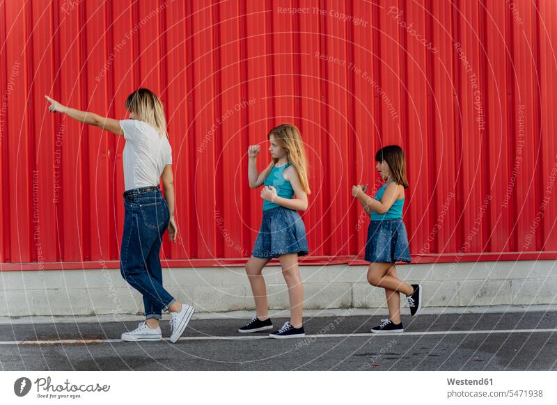 Mutter zeigt mit dem Finger, Töchter folgen Hosen Jeanshose T-Shirts entdecken gehend geht rote roter rotes aufgereiht hintereinander in einer Reihe