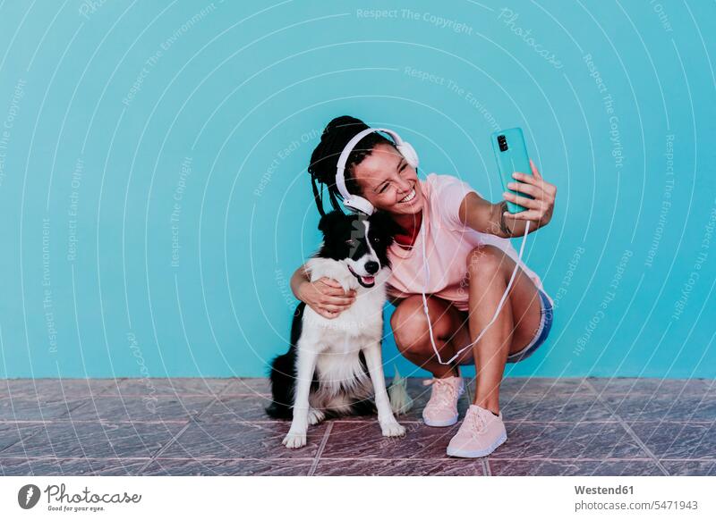 Glückliche Frau macht Selfie mit Border Collie Hund vor türkisfarbener Wand Farbaufnahme Farbe Farbfoto Farbphoto Spanien Außenaufnahme außen draußen im Freien