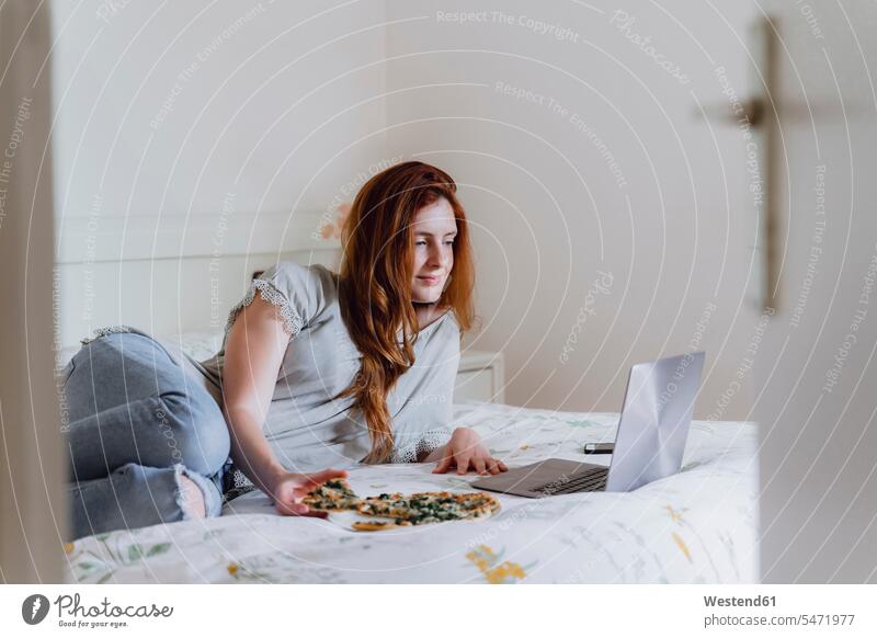 Schöne Frau liegt, während sie zu Hause einen Film schaut und Pizza im Bett genießt Farbaufnahme Farbe Farbfoto Farbphoto Spanien Freizeitbeschäftigung Muße