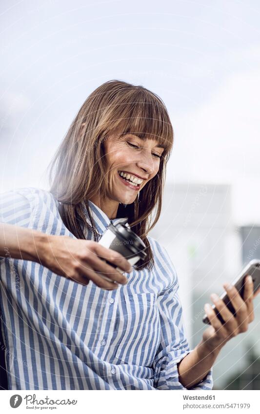 Geschäftsfrau liest Nachrichten auf ihrem Smartphone und trinkt Kaffee SMS Textnachricht Mitteilung Botschaft iPhone Smartphones Kaffeebecher Becher Pause