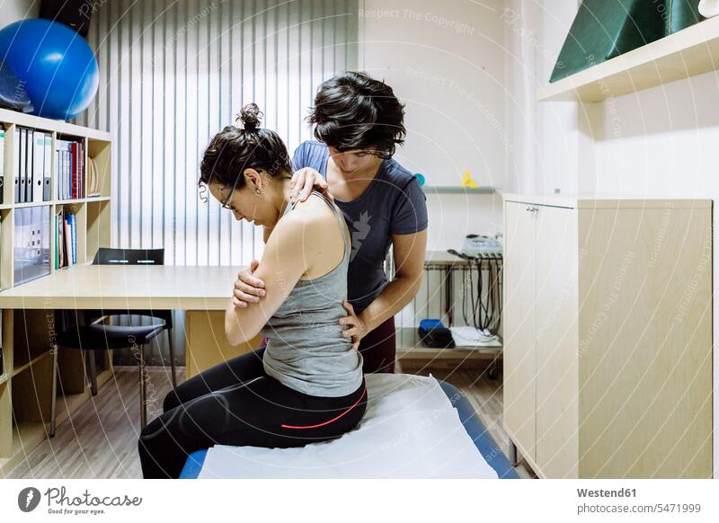 Weibliche Physiotherapeutin, die mit dem Klienten arbeitet Job Berufe Berufstätigkeit Beschäftigung Jobs Arbeit sitzend sitzt beweglich Biegsamkeit drinnen