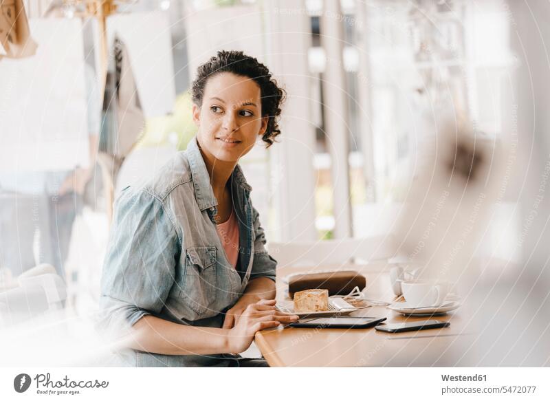 Junge Frau, die im Coworking Space arbeitet und Kuchen isst Cafe Kaffeehaus Bistro Cafes Café Cafés Kaffeehäuser essen essend Tablet Tablet Computer Tablet-PC