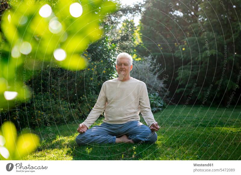 Älterer Mann meditiert im Garten entspannen relaxen entspanntheit relaxt Muße meditieren Blaetter Blätter Wiesen sonnig außen draußen im Freien am Tag