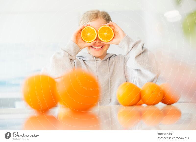 Lachendes Mädchen, das seine Augen mit Orangenhälften bedeckt Hälfte halbe halbiert halber Haelfte weiblich lachen bedecken abdecken zudecken Apfelsinen