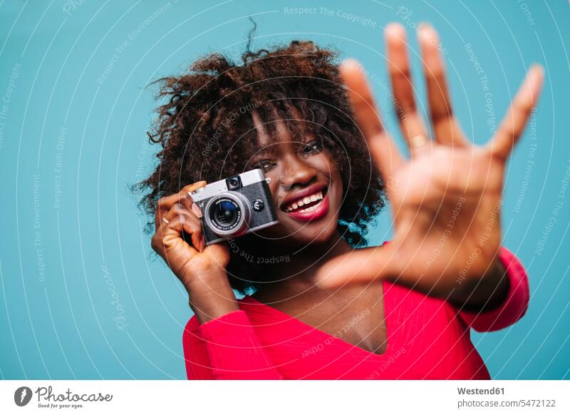 Porträt einer glücklichen jungen Frau, die eine Vintage-Kamera im Studio hält Leute Menschen People Person Personen Afrikanisch Afrikanische Abstammung