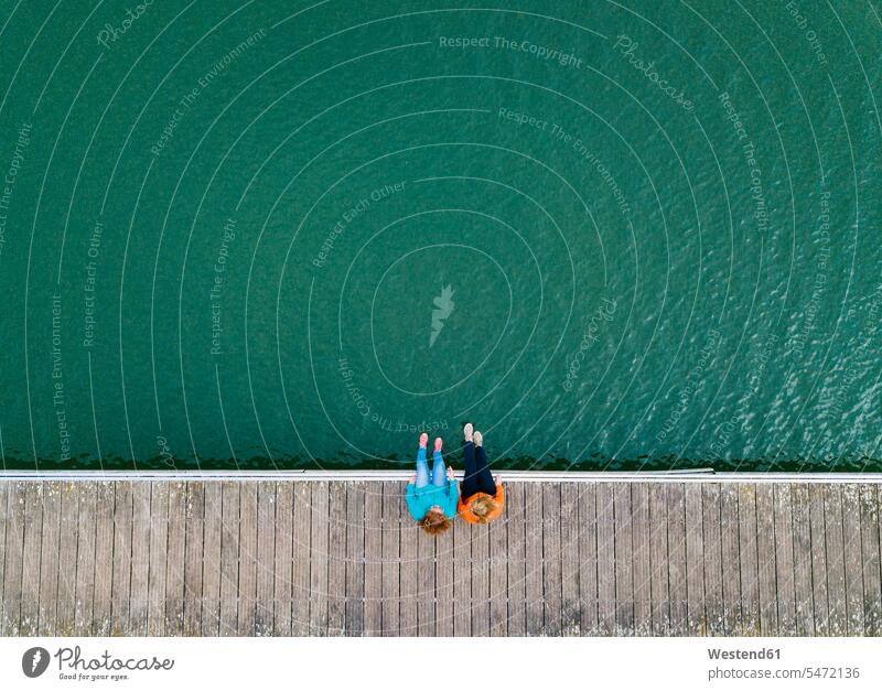 Zwei Freunde sitzen nebeneinander auf dem Bootssteg, Stausee Valdemurio, Asturien, Spanien entspannen relaxen sitzend sitzt reden geniessen Genuss