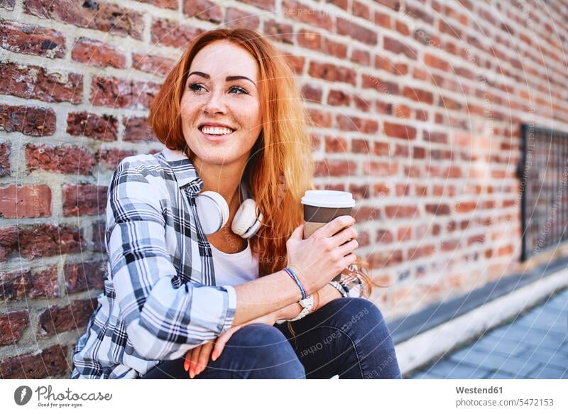Junge Frau sitzt an der Wand und hält eine Tasse Kaffee und schaut weg Leute Menschen People Person Personen Europäisch Kaukasier kaukasisch 1 Ein ein Mensch