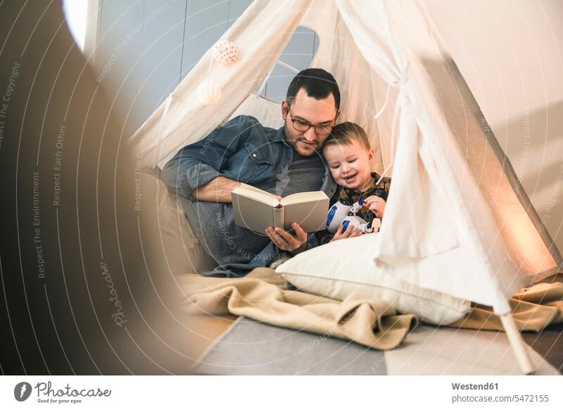 Vater und Sohn lesen gemeinsam ein Buch im Zelt zu Hause Bücher Zelte Gemeinsam Zusammen Miteinander Papas Väter Vati Vatis Papis Zuhause daheim Lektüre Söhne