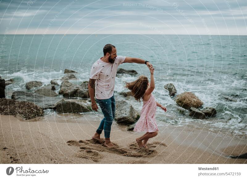 Tochter tanzt mit Vater am Strand Farbaufnahme Farbe Farbfoto Farbphoto Außenaufnahme außen draußen im Freien Abenddämmerung Dämmerung Abendstimmung abends
