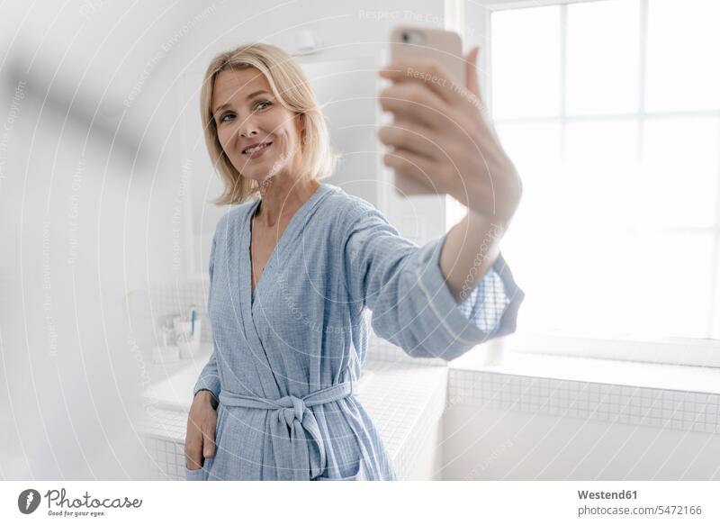 Lächelnde reife Frau nimmt ein Selfie im Badezimmer weiblich Frauen Selfies Zuversicht Zuversichtlich Selbstvertrauen selbstbewusst Vertrauen lächeln
