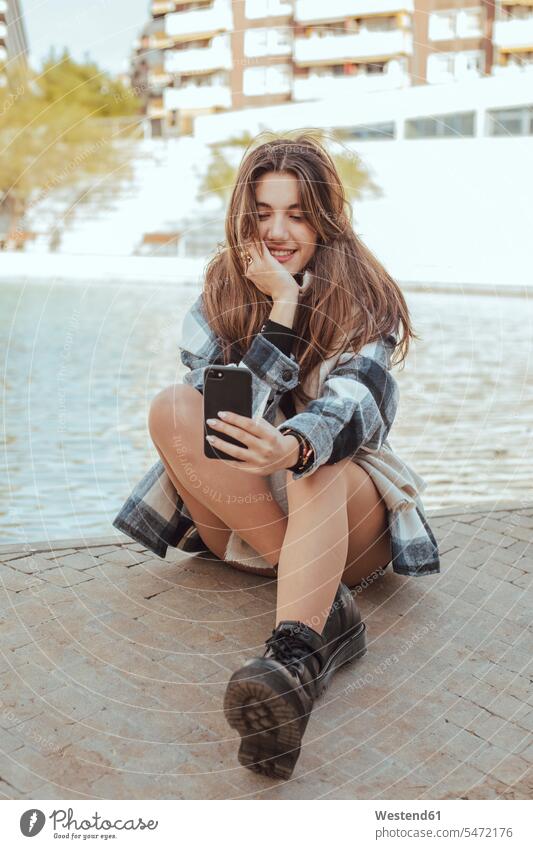 Junge brünette Frau, die ein Smartphone benutzt und ein Selfie macht Bilder Bildnis Fotos Schuhe Telekommunikation telefonieren Handies Handys Mobiltelefon