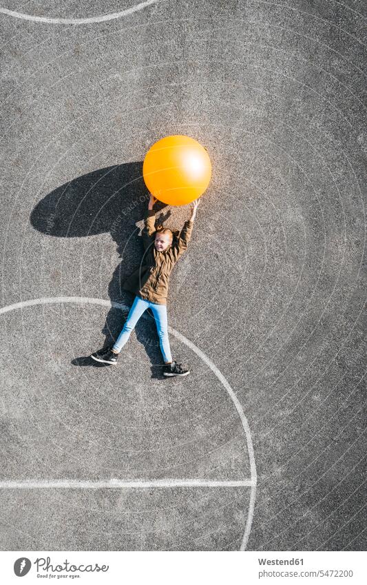 Österreich, Luftaufnahme eines Basketballfeldes, Mädchen mit großem Ball auf dem Boden liegend liegt Basketballplatz Basketballfelder Bälle weiblich Sport Kind