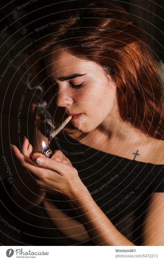 Junge Frau raucht Marihuana zu Hause Tabak Zigaretten Feuerzeuge daheim Flammen Realitätsflucht Weltflucht Muße Qualm Raum Räume Wohnen Wohnraum Wohnräume