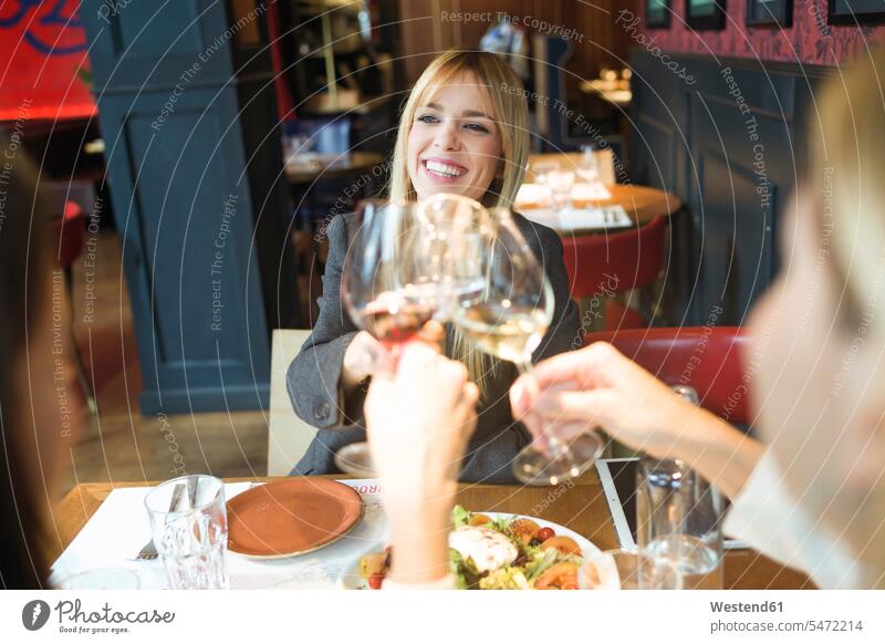 Lächelnde Geschäftsfrauen treffen sich und stoßen in einem Restaurant auf Wein an Freunde Kameradschaft Freundin geschäftlich Geschäftsleben Geschäftswelt