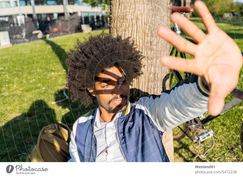 Lässiger Geschäftsmann, der eine Pause im Stadtpark macht und seine Augen abschirmt, Barcelona, Spanien Leute Menschen People Person Personen Afrikanisch