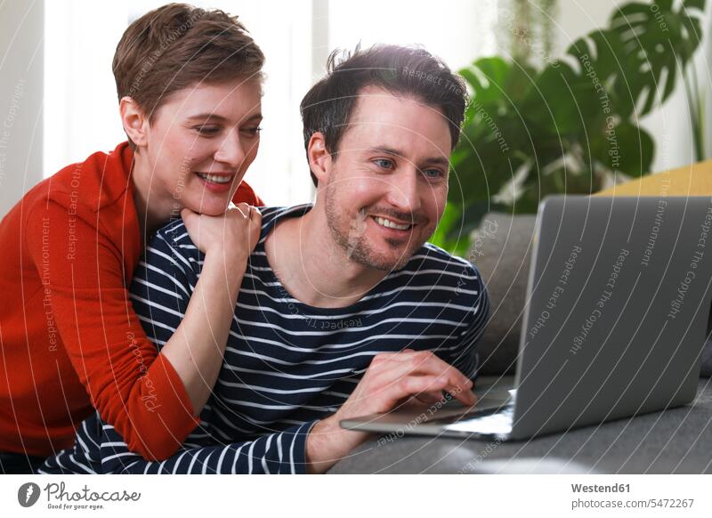 Zu Hause sitzendes Ehepaar mit Laptop Paar Pärchen Paare Partnerschaft Notebook Laptops Notebooks Laptop benutzen Laptop benützen Frau weiblich Frauen sitzt