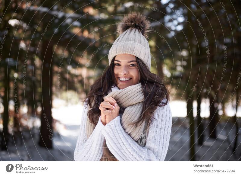 Porträt einer glücklichen jungen Frau in Strickwaren im Winterwald Glück glücklich sein glücklichsein Wald Forst Wälder winterlich Winterzeit gestrickt weiblich