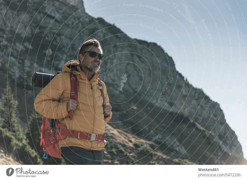 Österreich, Tirol, lächelnder Mann mit Sonnenbrille beim Wandern in den Bergen Männer männlich Gebirge Berglandschaft Gebirgslandschaft Gebirgskette Gebirgszug