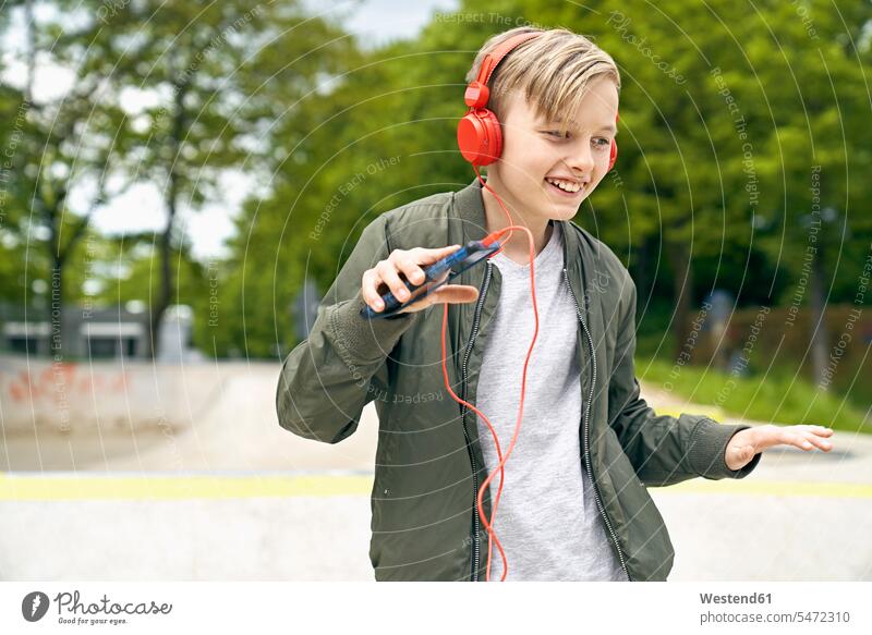Junge mit Kopfhörer tanzt beim Musikhören auf Smartphone Kopfhoerer Buben Knabe Jungen Knaben männlich cool Coolness hoeren lächeln iPhone Smartphones Freizeit